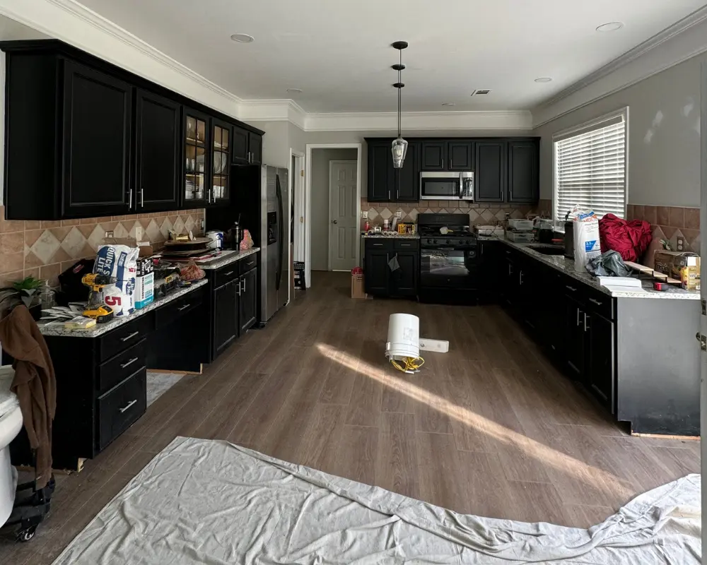 An outdated kitchen with dark black cabinets, cluttered countertops, brown tile backsplash, and a drop cloth on the floor before a professional remodel by Center Cabinet in Roswell, GA.